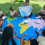Children exploring a large floor world map at Brainy Explorers Montessori