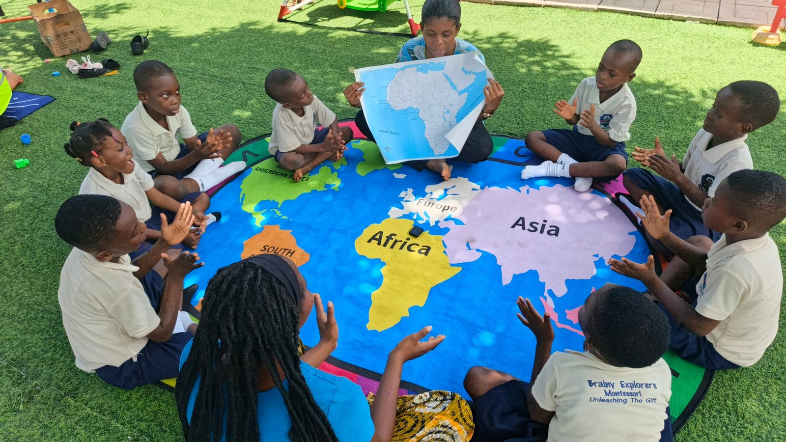 Children exploring a large floor world map at Brainy Explorers Montessori