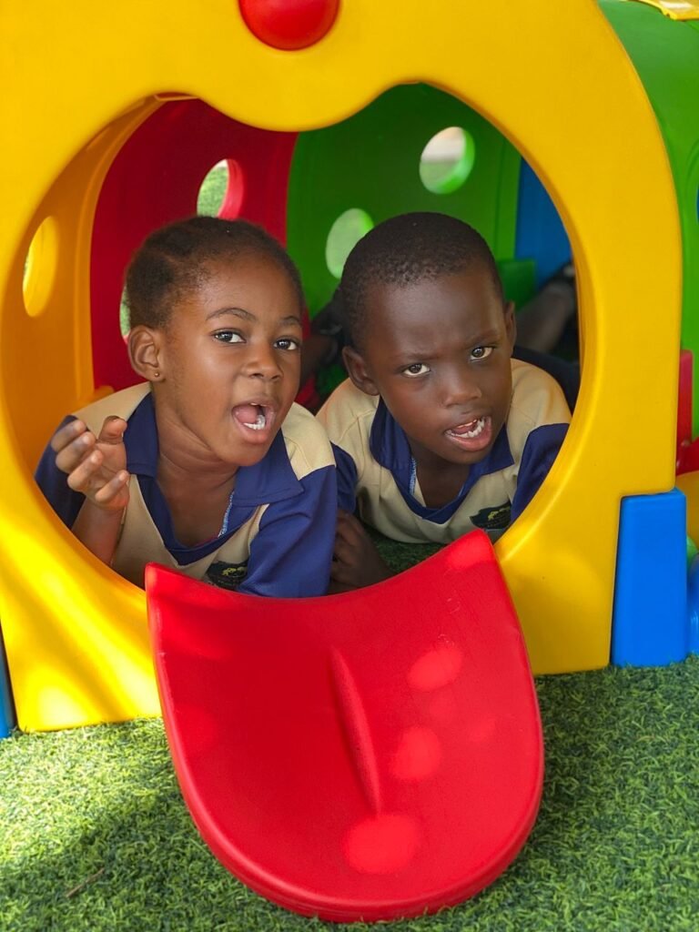 Two Brainy Explorers pupils smiling inside a colourful playground tunnel