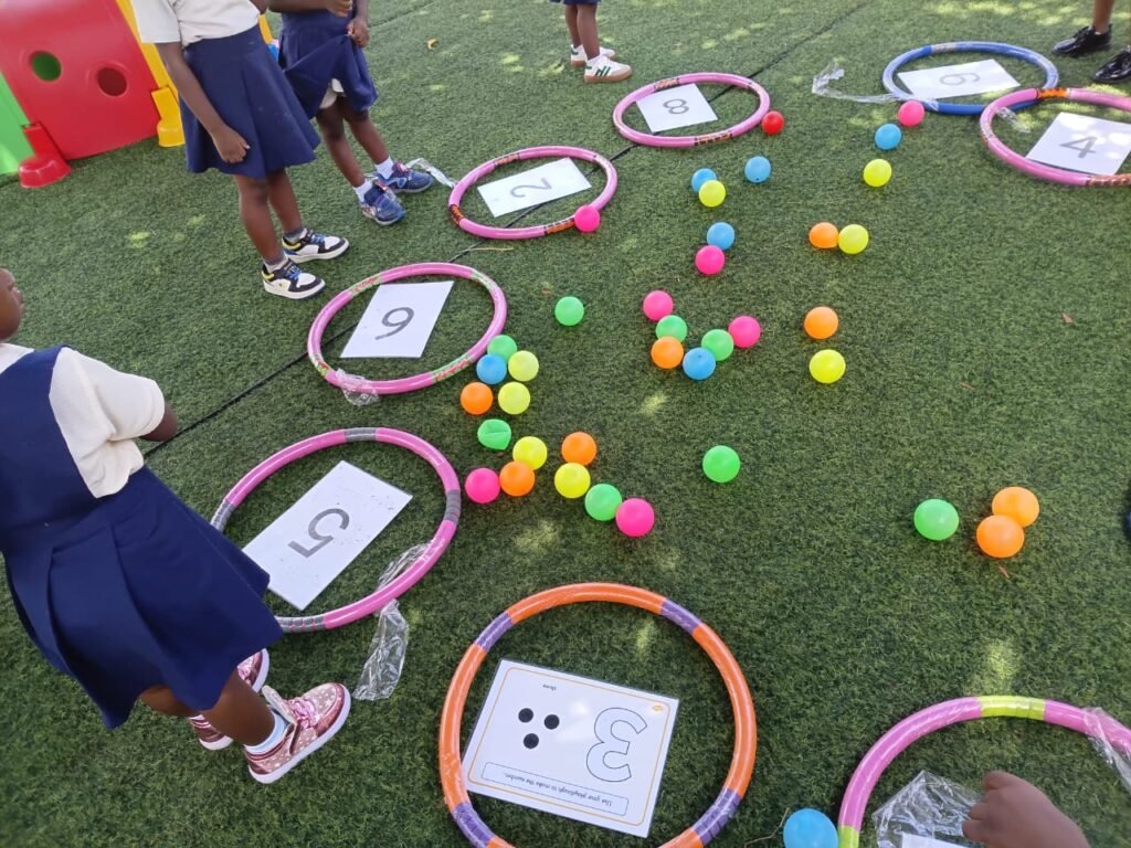 Outdoor Montessori counting activity with number cards in hoops and coloured balls