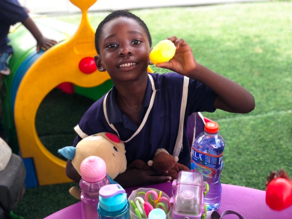 Smiling pupil holding a toy at the activity table